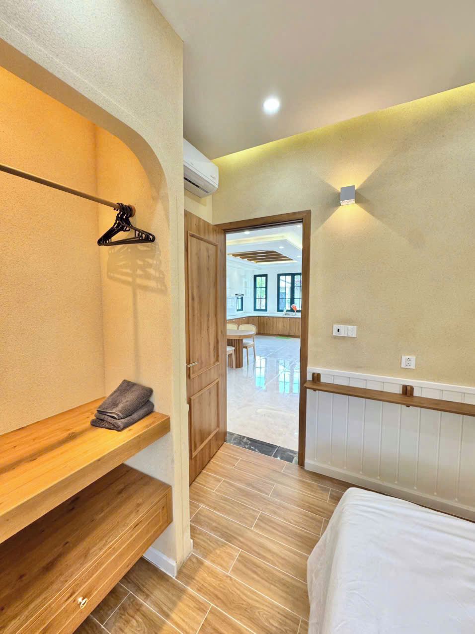 Ein modernes Hotelzimmer mit einer Holzbank, einem Bett und Blick ins Freie.