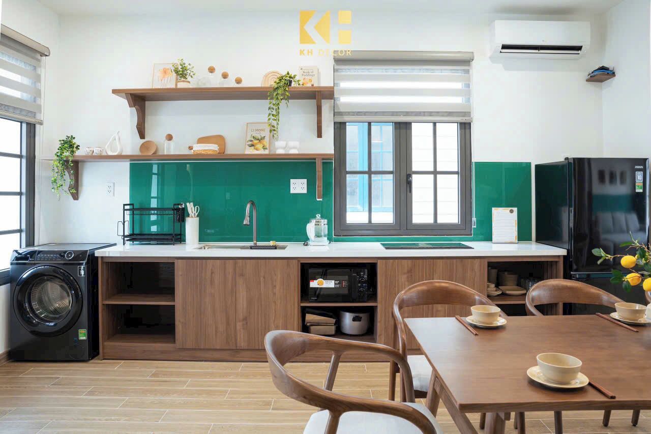 Una cocina compacta con lavadora, una zona de comedor con sillas y una mesa, y un salpicadero verde.