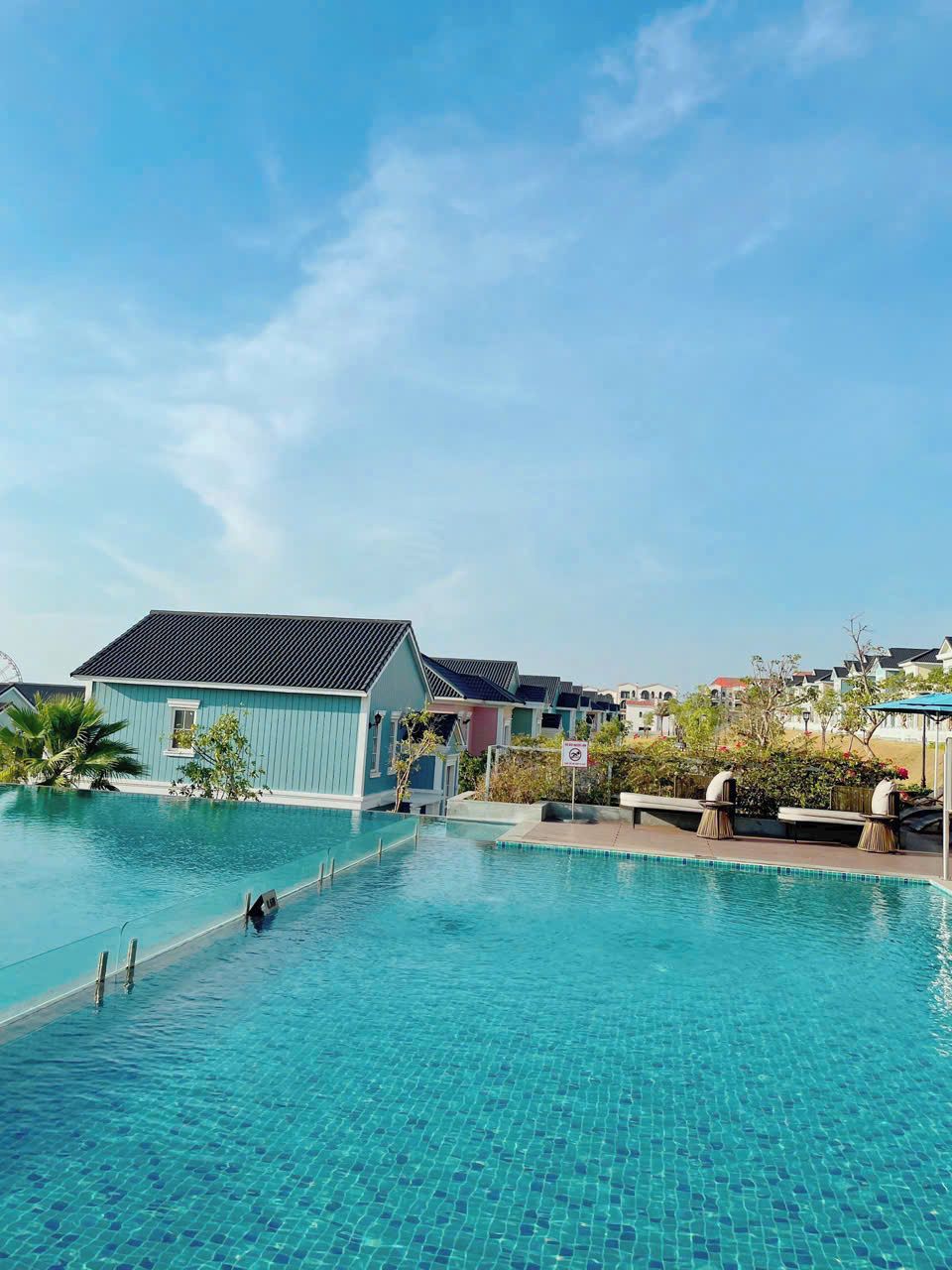A swimming pool with clear blue water, surrounded by buildings with blue and white exteriors.
