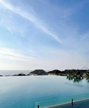 A clear blue sky with a large infinity pool, a Ferris wheel, and several buildings with dark roofs in the background. - Dan - Villa Novaworld Phan Thiet (Tien Thanh)