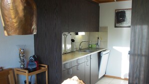 Pieni, käytännöllinen keittiö, jossa on pesuallas, kaappeja ja työtaso.