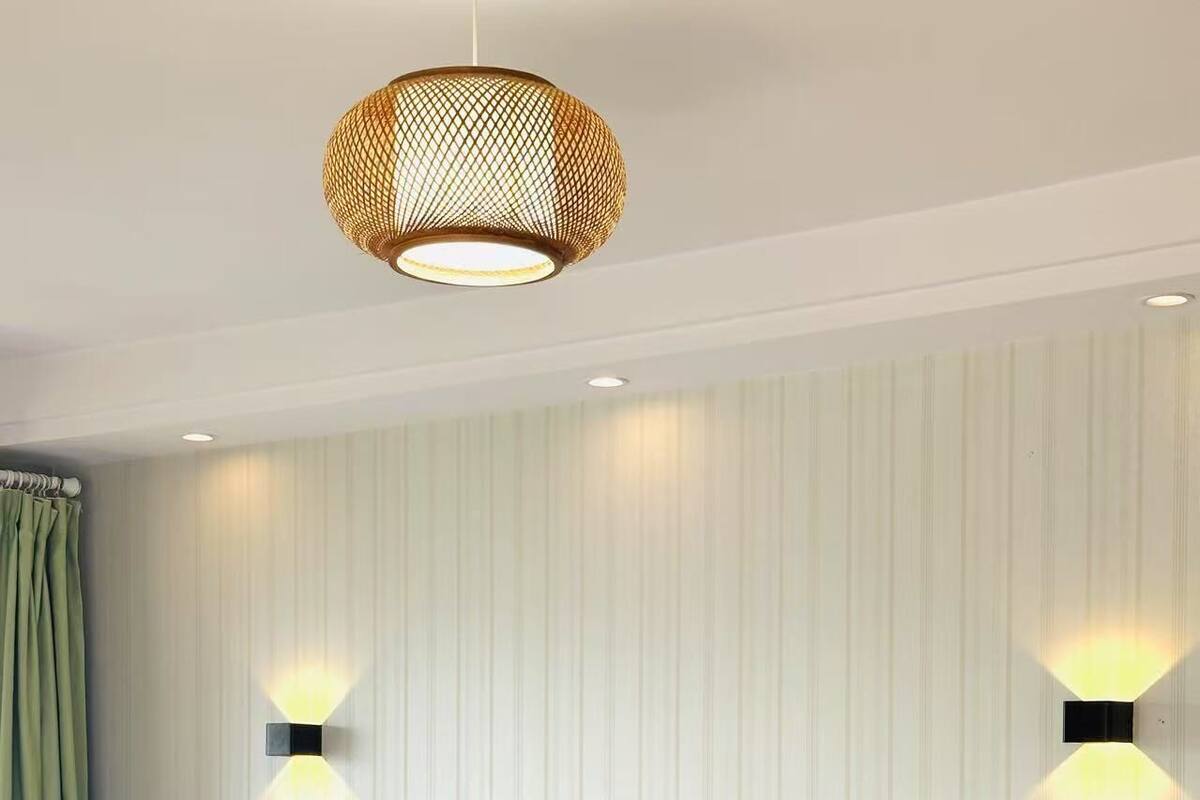 Habitación de hotel con cama, dos luces empotradas en la pared, una lámpara colgante y una mesita de noche con lámpara.