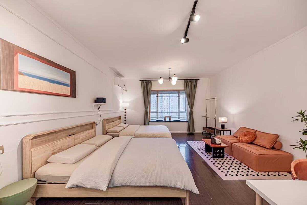 Habitación de hotel con dos camas, un sofá, un escritorio y una ventana con cortinas.