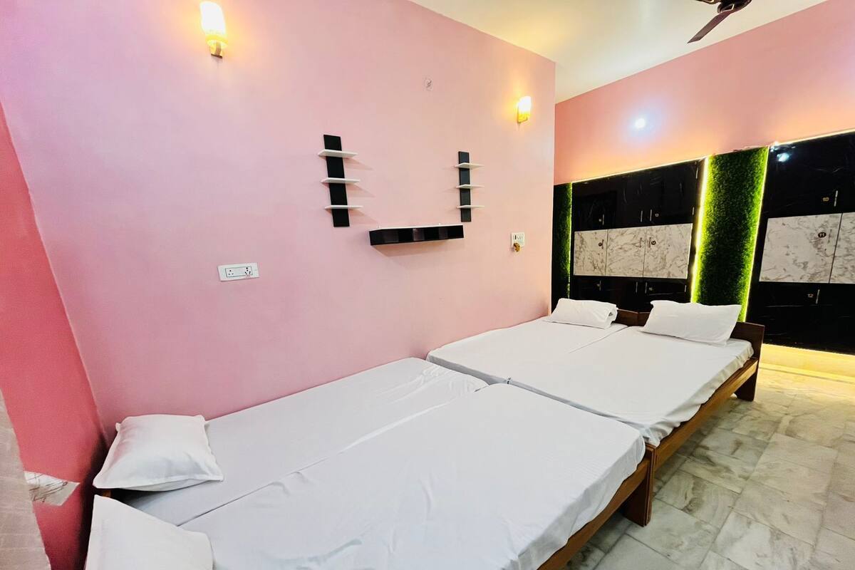 A hotel room with two single beds, a marble floor, a pink wall, and a modern headboard with a green accent.