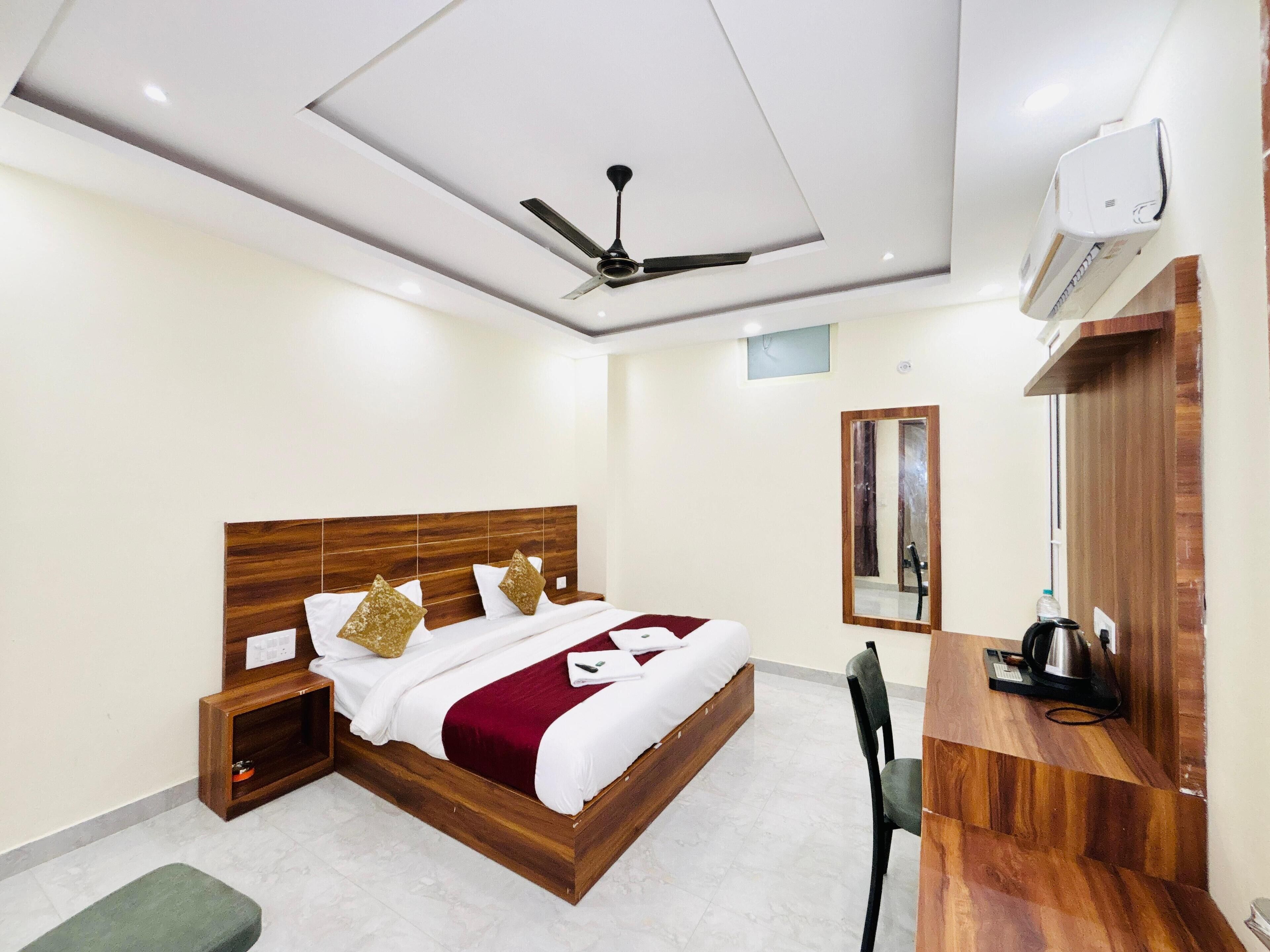 A modern hotel room with a wooden bed, a ceiling fan, a built-in desk, and a mirror.