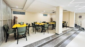 A conference room with multiple tables and chairs, a staircase, and a ceiling fan. - Hotel Hitam (Rishikesh)