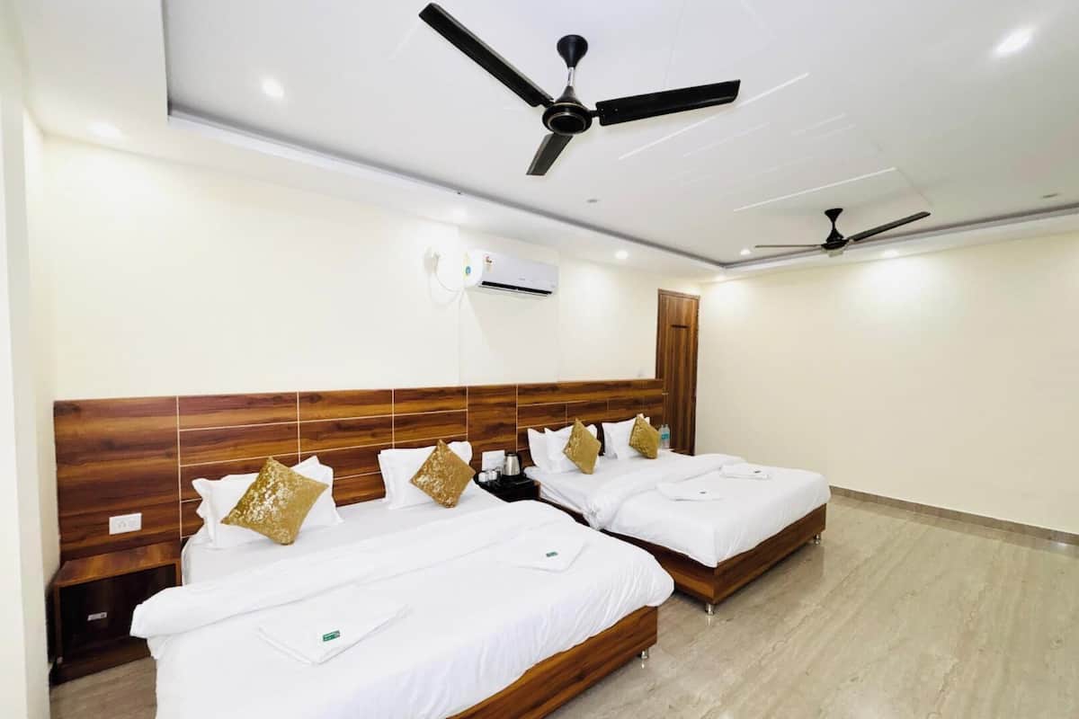 A hotel room with two beds, wooden headboards, white bedding, and ceiling fans.