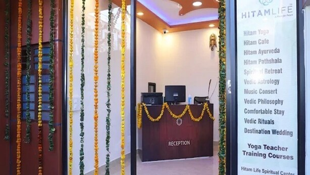 A reception area with a reception desk, a computer, and a phone. There are garlands hanging above the entrance. - Hotel Hitam (Rishikesh)