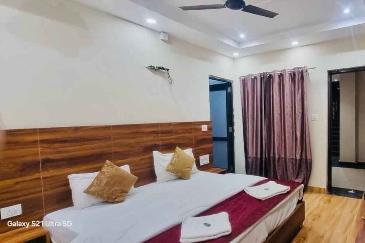A hotel room with two beds, a ceiling fan, a mirror, and a door leading to another room.