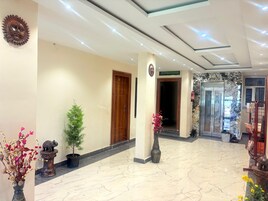 A hotel lobby with a marble floor, wooden doors, and decorative vases.