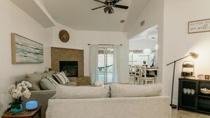 A modern living room with a sofa, a small table with a lamp, and a fireplace. - Spacious 4BDRM with a Stunning Pool+Game Room and Firepit (Bakersfield)
