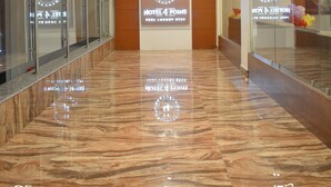 A hotel reception area with a marble floor, glass railings, and a modern ceiling design. - Hotel 4 Point (Gandhinagar)