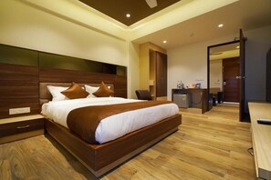 A modern hotel room with a large bed, wooden headboard, and a desk with a chair. - Hotel 4 Point  (Gandhinagar)