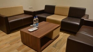 A seating area with a brown leather sofa and a wooden coffee table. - Hotel 4 Point (Gandhinagar)