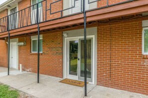 Un edificio in mattoni con un balcone, una porta con un vetro e un tappetino d'ingresso con la scritta “COME IN”.