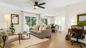 Ein geräumiges Wohnzimmer mit einer Couch, Sesseln, einem Couchtisch und einem Essbereich mit Tisch und Stühlen.