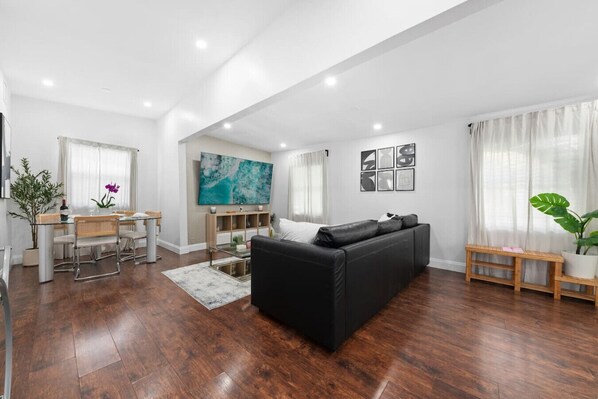 A modern living room with a black sofa, wooden dining table, and a large abstract painting on the wall. - Upscale Home - CityPlace & Convention Center (West Palm Beach)