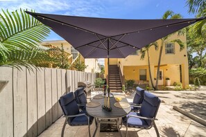 An outdoor patio with a table and chairs, a large umbrella, and a wooden fence. - Upscale Home - CityPlace & Convention Center (West Palm Beach)