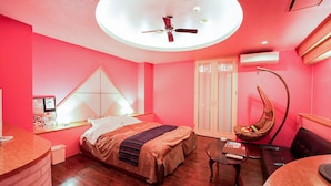 Un dormitorio moderno con cama, escritorio, silla, sillón colgante y ventilador de techo.