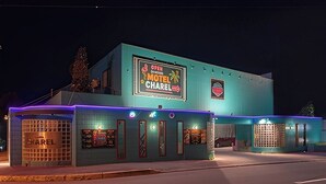 Un motel con un letrero de neón, un coche estacionado afuera y un árbol de Navidad.