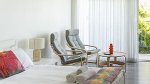 A hotel room with a bed, two armchairs, a small table, and a view of greenery outside. - Garigal Retreat with Pool access (Forestville)
