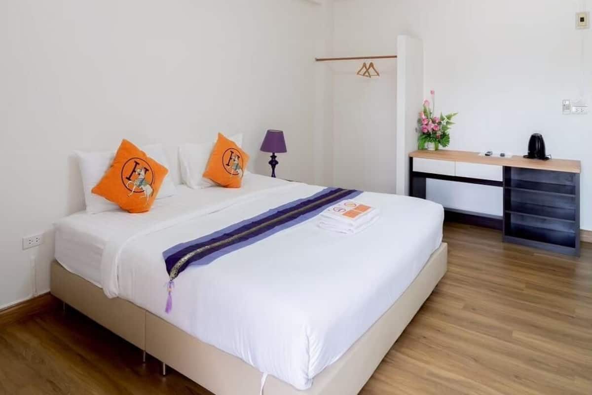 Una habitación de hotel moderna con una cama grande, un escritorio y un armario.