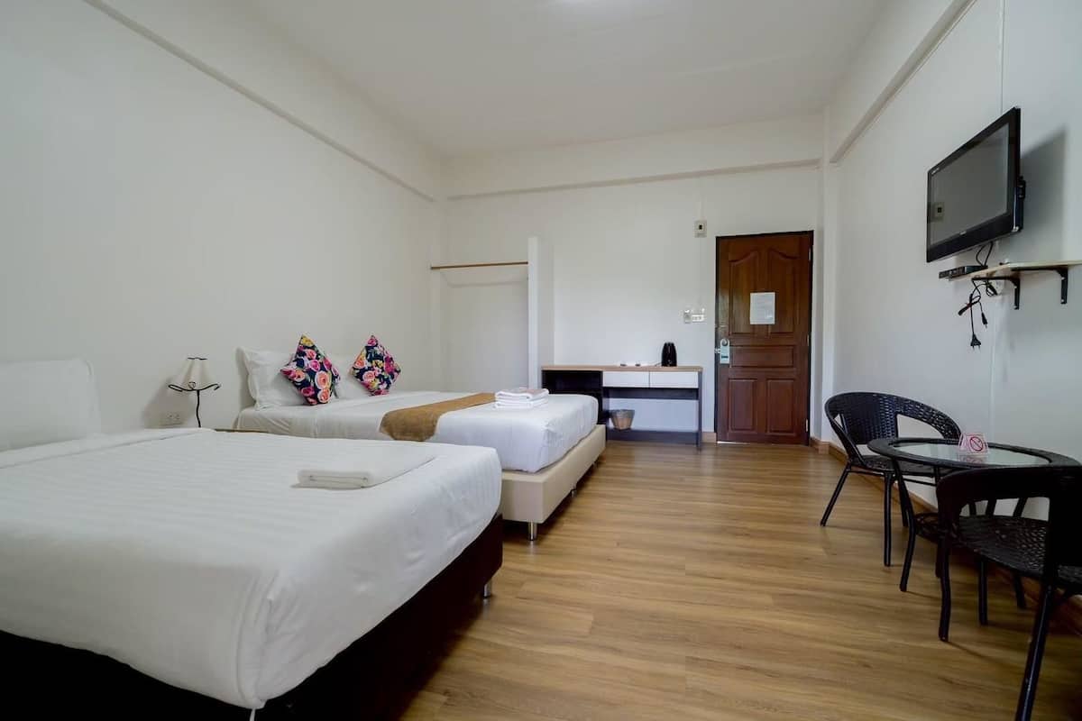 Habitación de hotel con dos camas, un escritorio, una silla y un televisor.