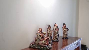 Et indrammet kunstværk på væggen, et træbord med figurer, og en lampe.