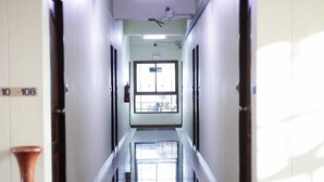 En lång, smal hall med ett reflekterande golv, dörrar på båda sidor och ett fönster längst ner.