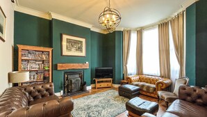 A living room with leather sofas, a fireplace, a bookshelf, and a television.