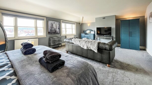 A bedroom with a bed, a dresser, a television, and a wardrobe.