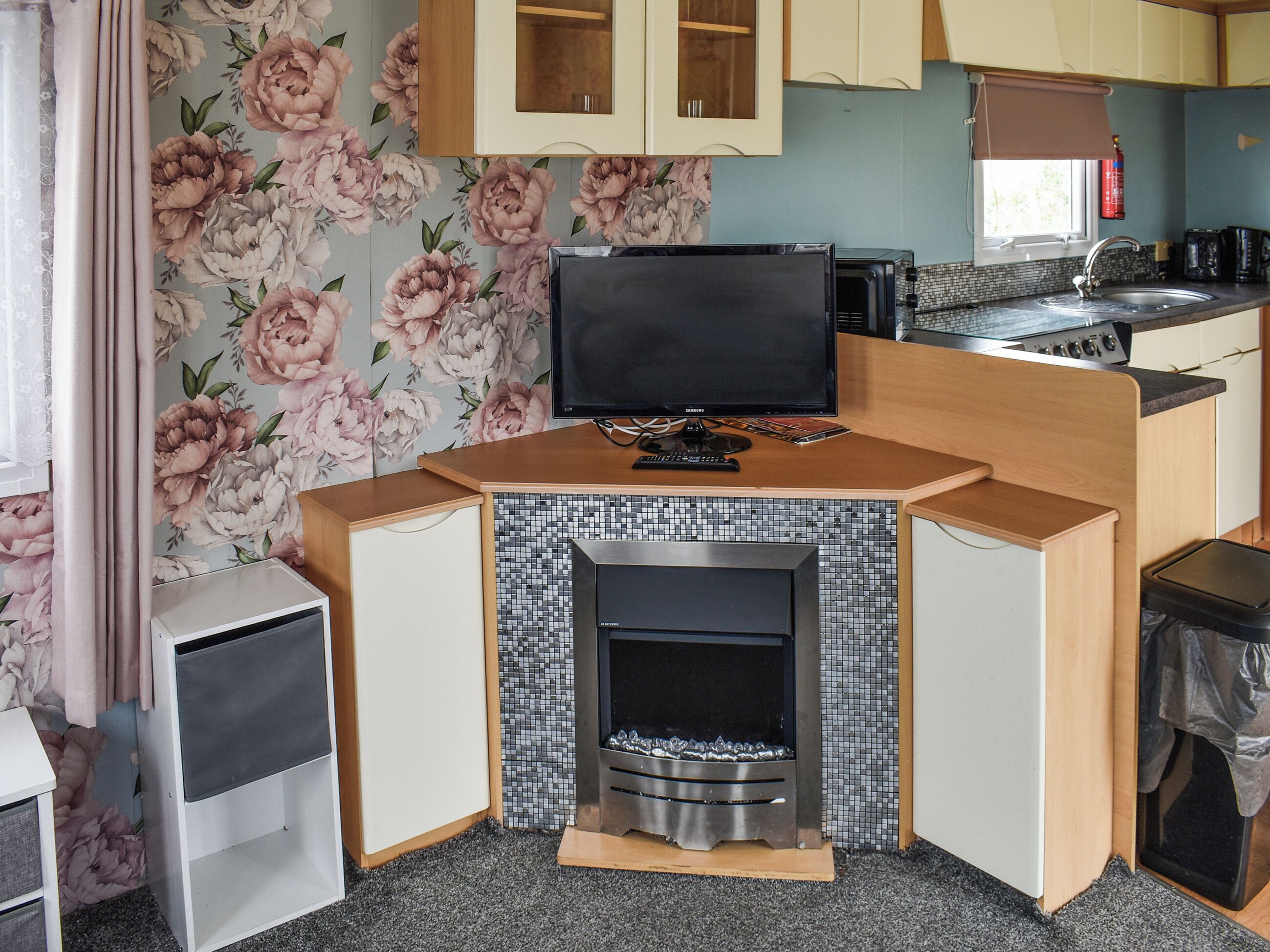 A compact kitchen with a TV, a small fireplace, and a tiled backsplash.
