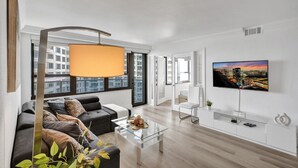 A modern living room with a sofa, coffee table, and a TV mounted on the wall. - Gorgeous Ocean View 3BD Condo in Beachfront Resort 907 (Miami Beach)