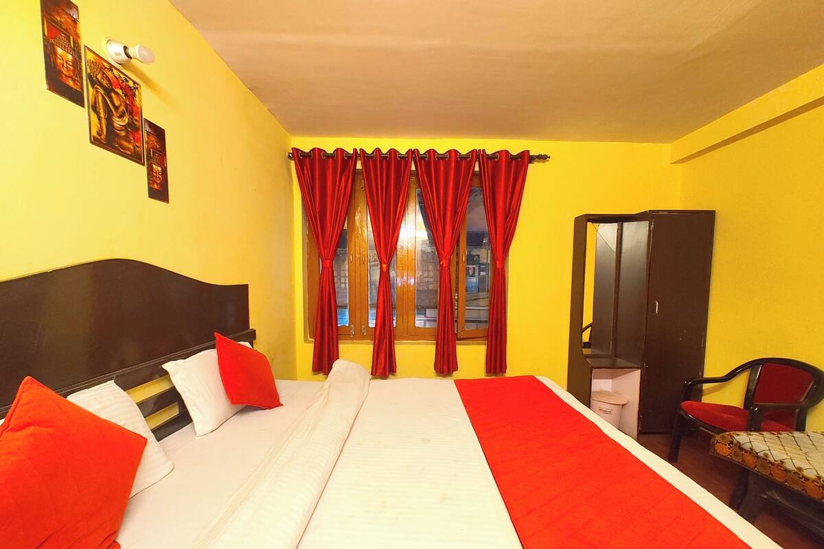 A room with a bed, red curtains, a wardrobe, and a chair.