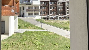 A view from inside a building looking out at a residential area with modern buildings, a grassy area, and mountains in the background. - Haus Salü 5 by Interhome (Saas-Fee)