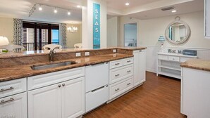 Una cocina moderna con una isla central, muebles blancos y vista al mar.