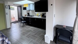 A modern kitchen with black cabinets, a white countertop, and a black TV mounted on the wall. - Pet friendly loft with private terrace (Ciudad de México)