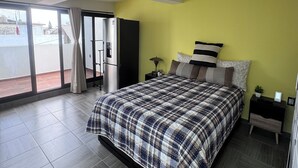 A bedroom with a large bed, a nightstand, a lamp, and a view through a sliding glass door to an outdoor area. - Pet friendly loft with private terrace (Ciudad de México)