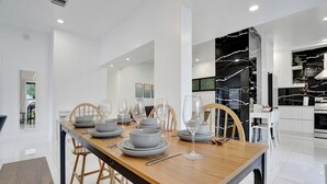 Un espace repas moderne avec une table en bois dressée pour quatre personnes, entourée de chaises blanches.