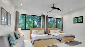 Une chambre moderne avec deux lits, un canapé et de grandes fenêtres avec des rideaux.