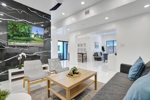 Un salon moderne avec un téléviseur à écran plat, une table basse en bois et un canapé gris.