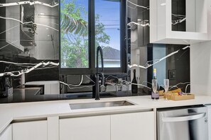 Een moderne keuken met een groot raam, een roestvrijstalen spoelbak en een vaatwasser.