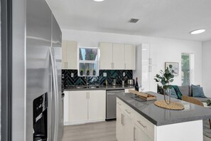 Eine moderne Küche mit weißen Schränken, einer schwarzen Spritzschutzwand und Edelstahlgeräten.