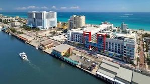 A coastal cityscape with high-rise buildings, a marina, and a prominent red and blue commercial building. - New Luxury Beachfront Condo with Rooftop Pool (Hollywood)