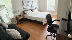Quarto com cama, escrivaninha, cadeira, sofá e ventilador de teto.