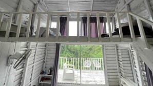 A cabin with a balcony, white walls, and a wooden ceiling.