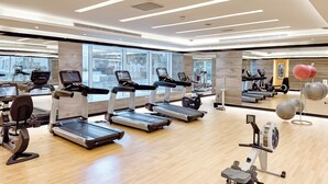 Een moderne sportschool met loopbanden, hometrainers en fitnessballen.