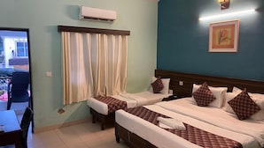 Ein Hotelzimmer mit zwei Betten, einem Essbereich und einer Klimaanlage.