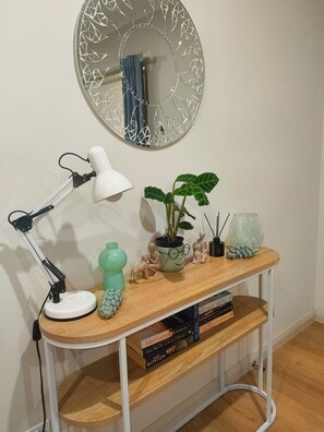 Un bureau avec une lampe de bureau blanche, une plante en pot, des figurines décoratives et des livres.
