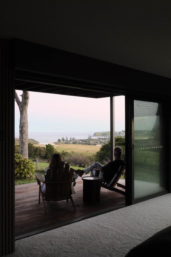 A room with a large sliding glass door leading to an outdoor deck with two chairs and a small table.